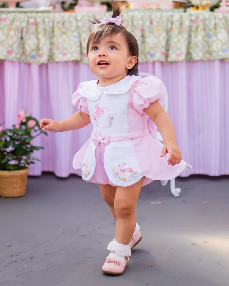 Bebê caminhando com romper rosa bordado